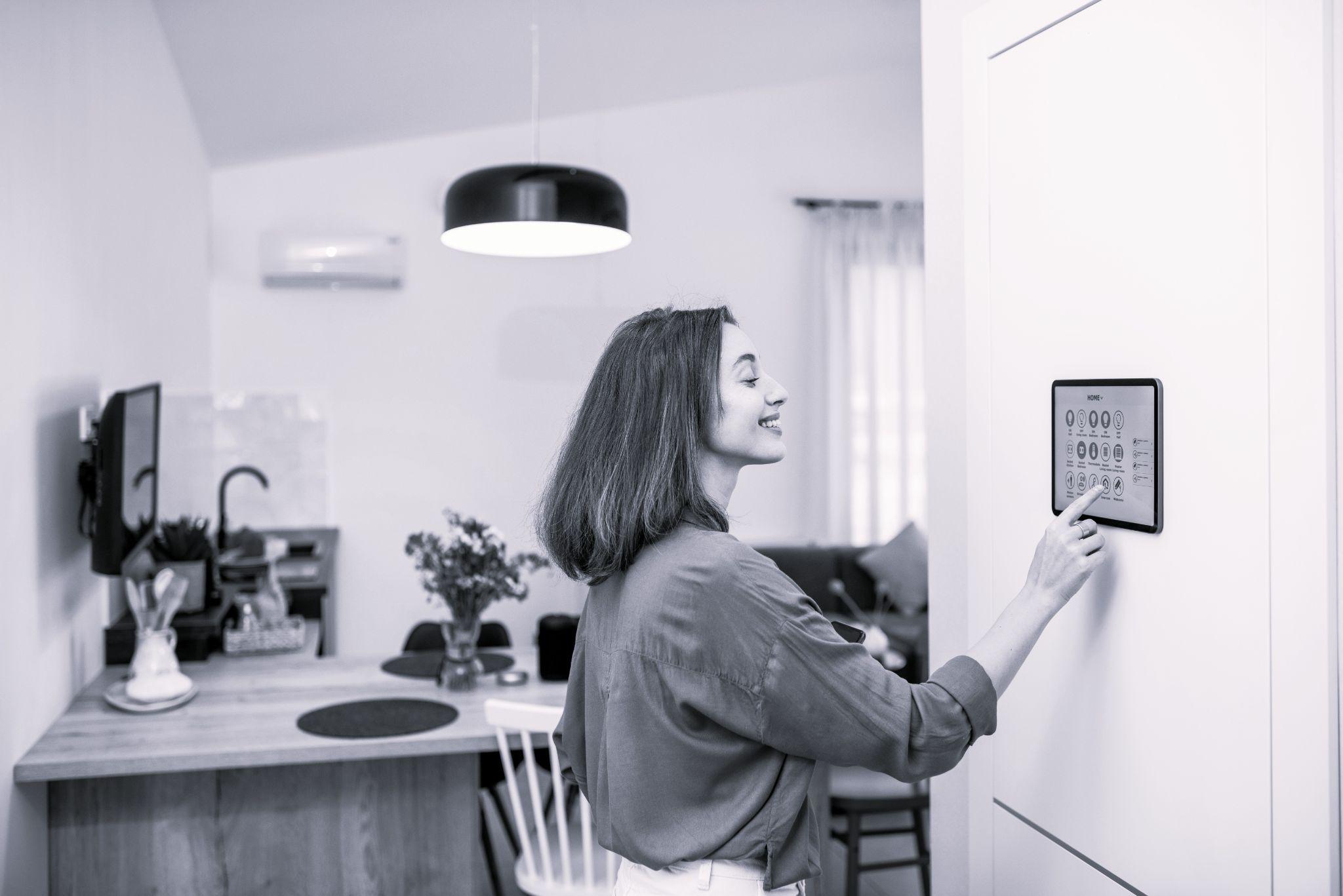 A woman using a smart home tablet on the wall of her rental property A woman using a smart home tablet on the wall of her rental property