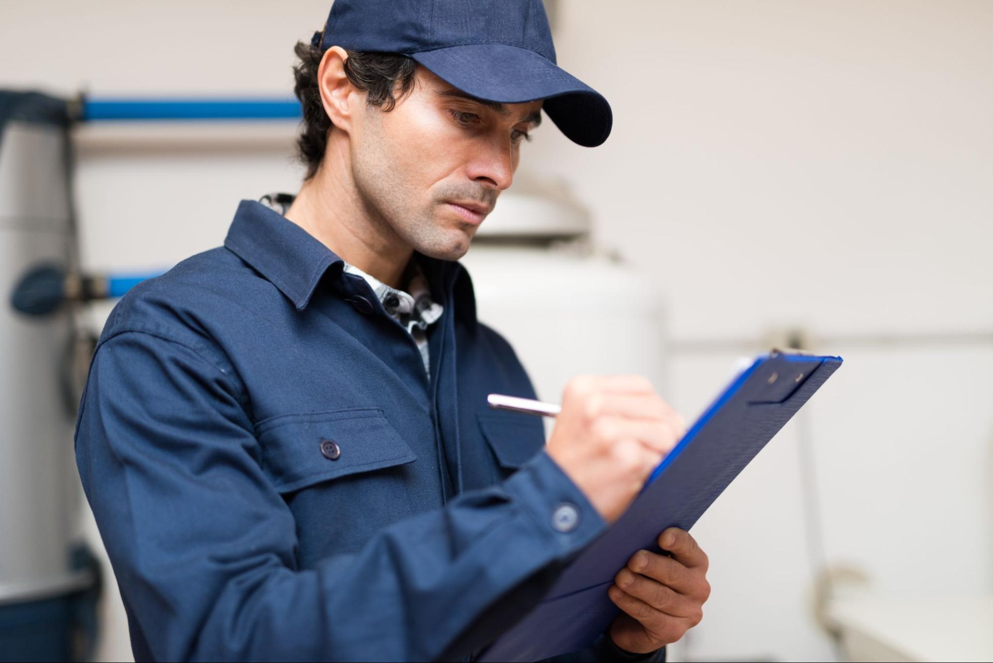 A maintenance man writing on a clipboard