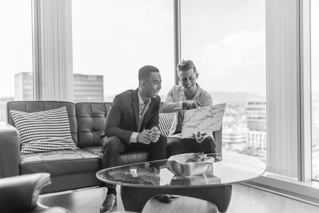 two men in suit sitting on sofa using laptop two men in suit sitting on sofa using laptop
