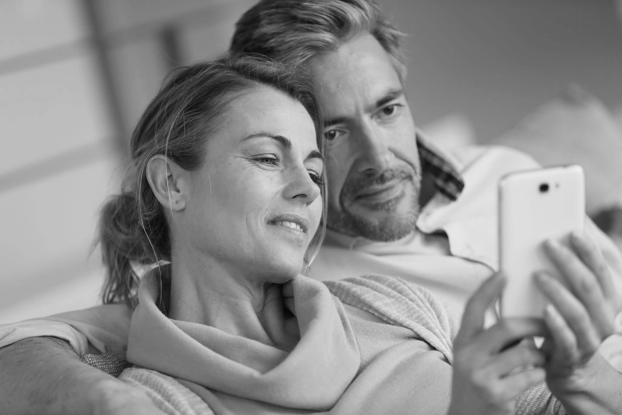 Mature couple sitting in sofa and using smartphone