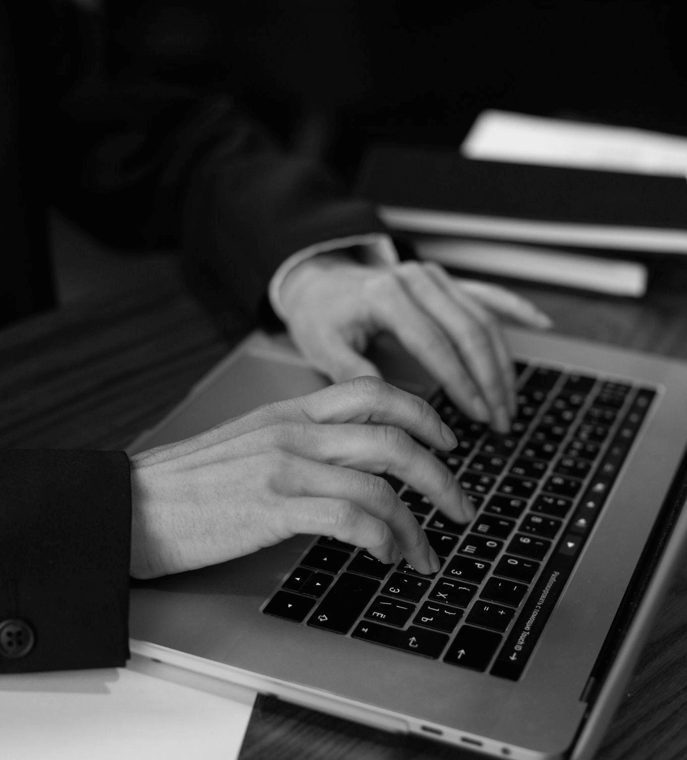 grayscale photo of a person typing on a laptop