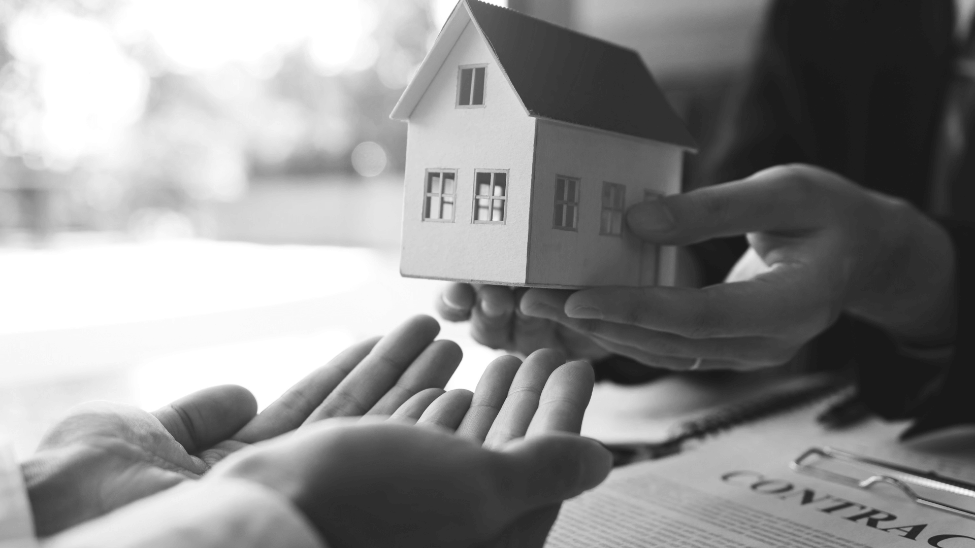 Real estate agent congratulations to new buyer by giving house model to client in the agency office.