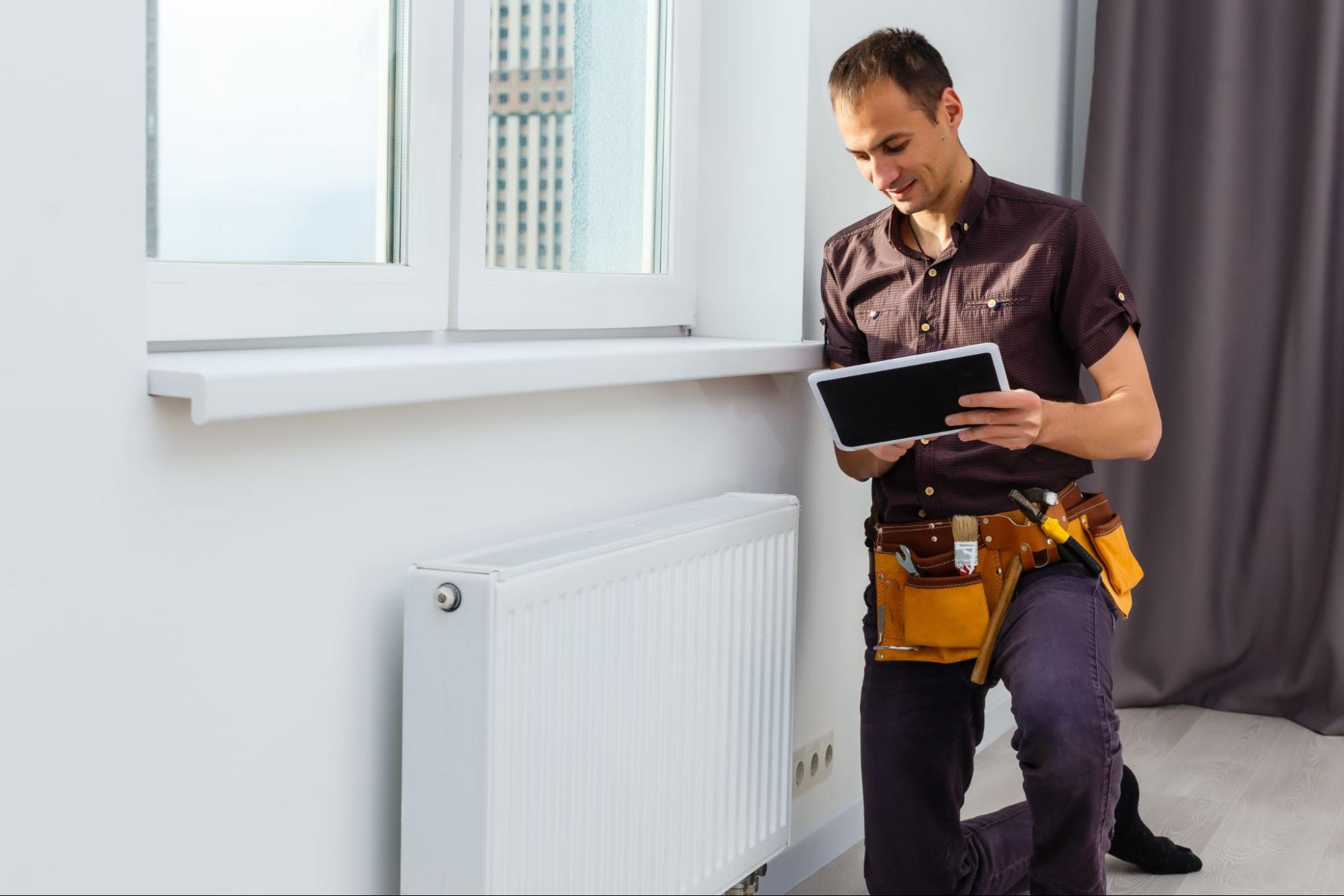 An apartment maintenance man inspecting a heating unit