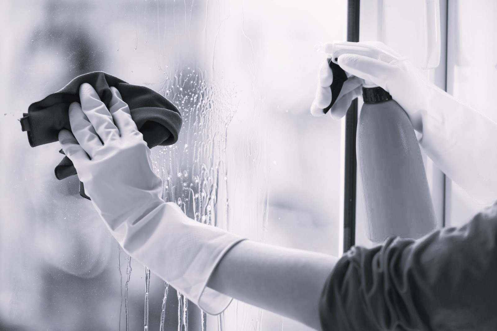 Gloved hand cleaning window rag and spray