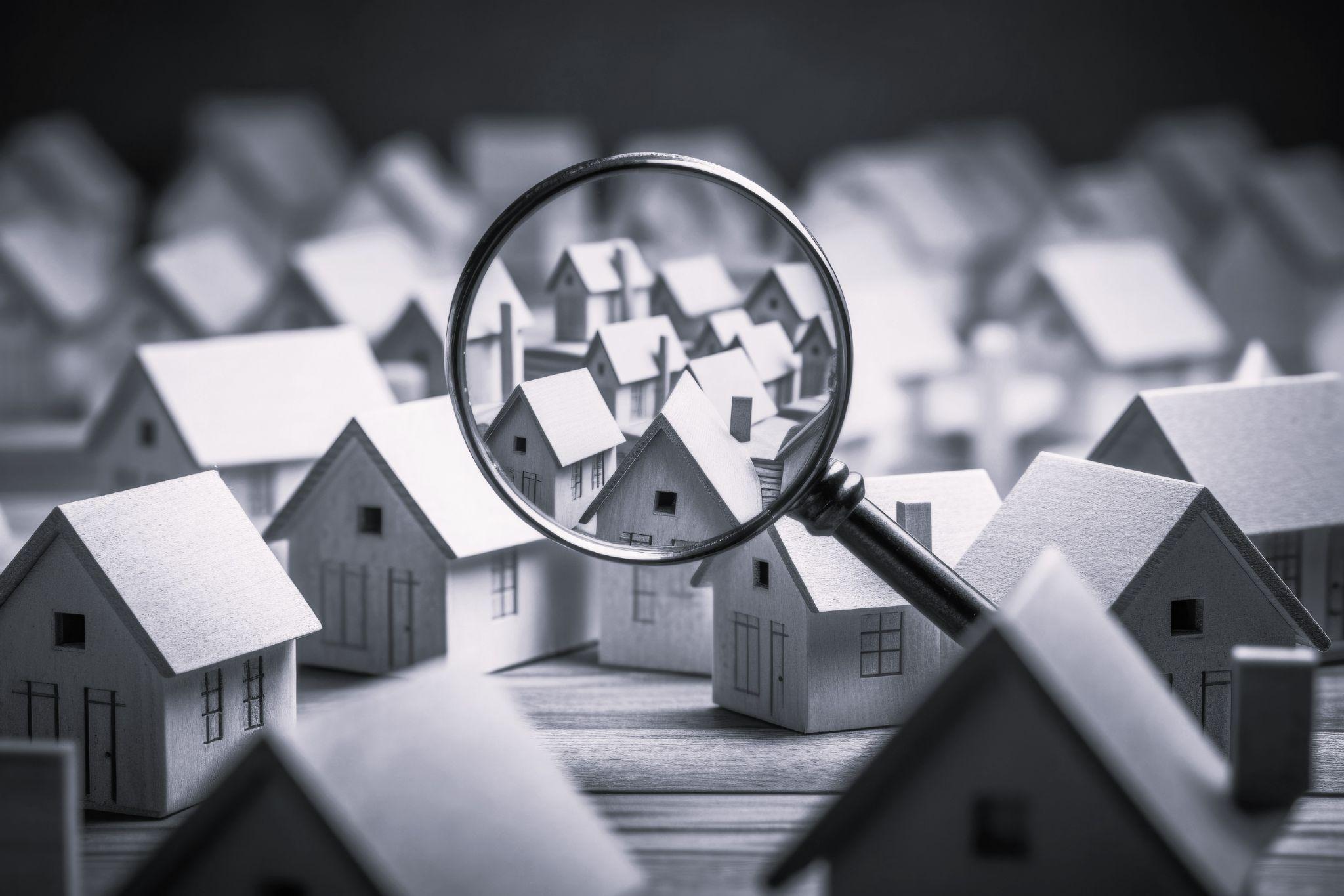 Searching new house for purchase. Rental housing market. Magnifying glass near residential building.