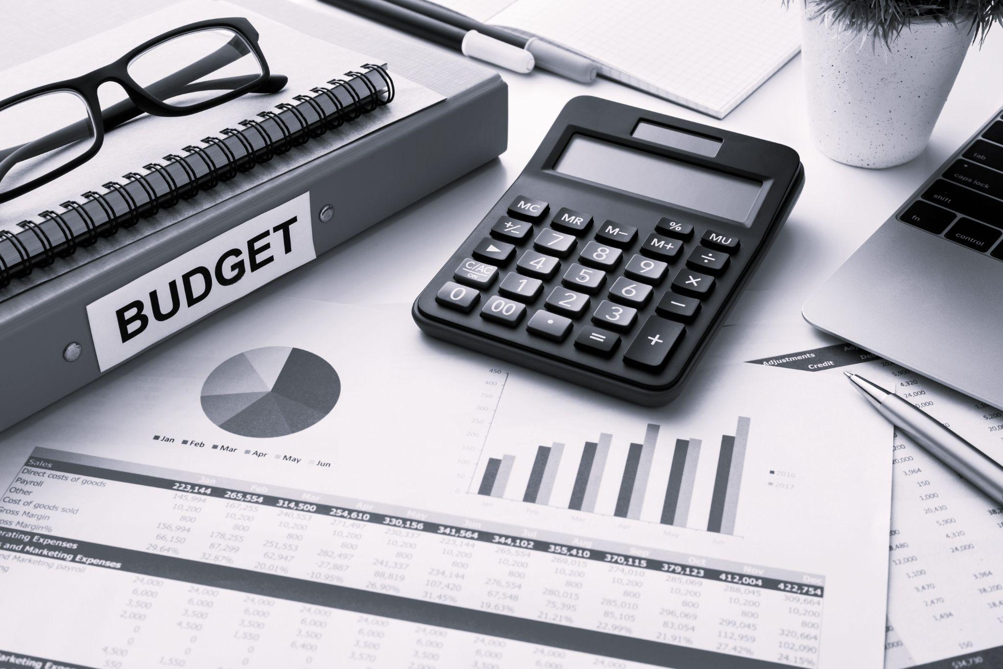 Budget plan with calculator on white table