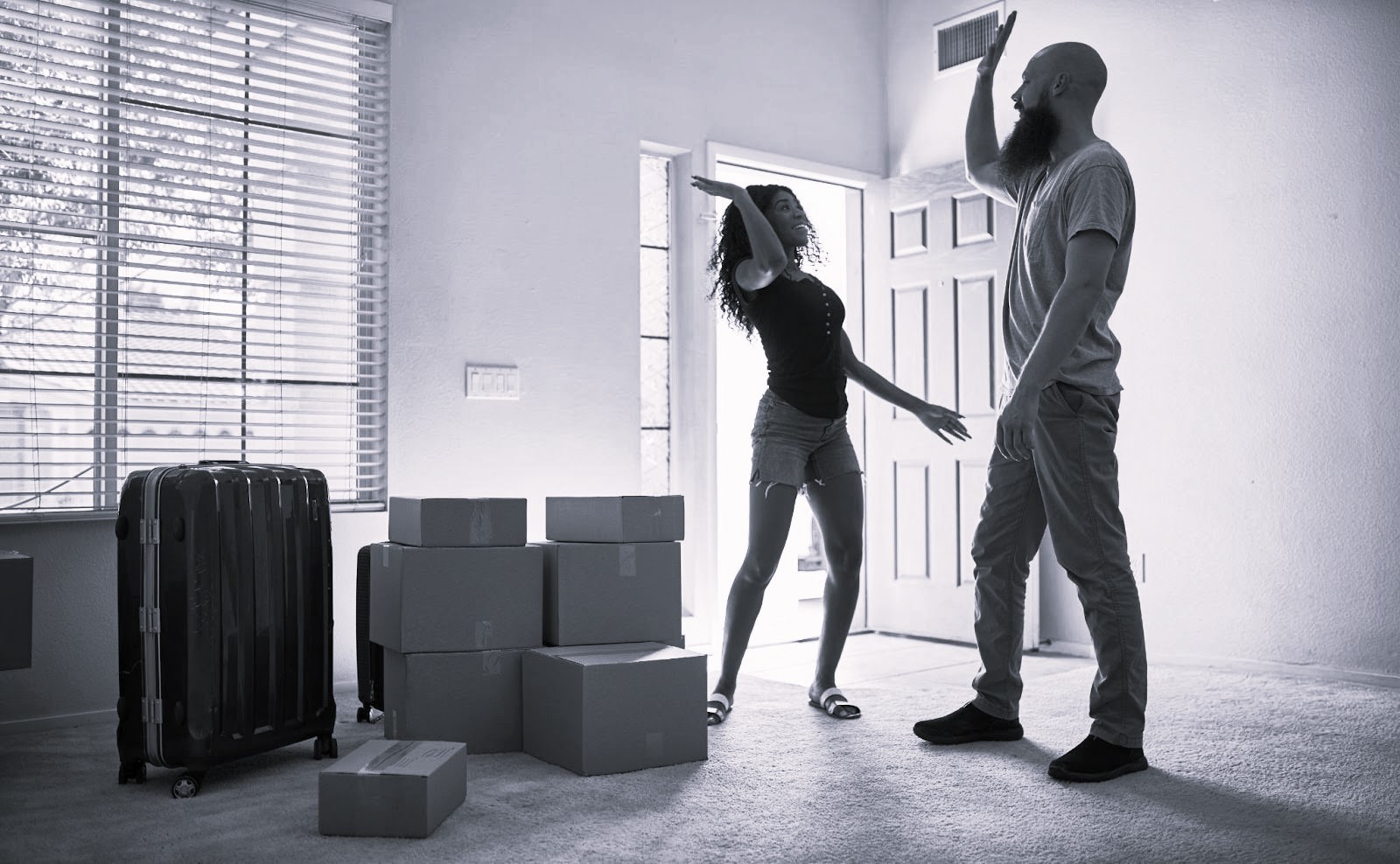 Couple high fiving in celebration in a room full of packed boxes