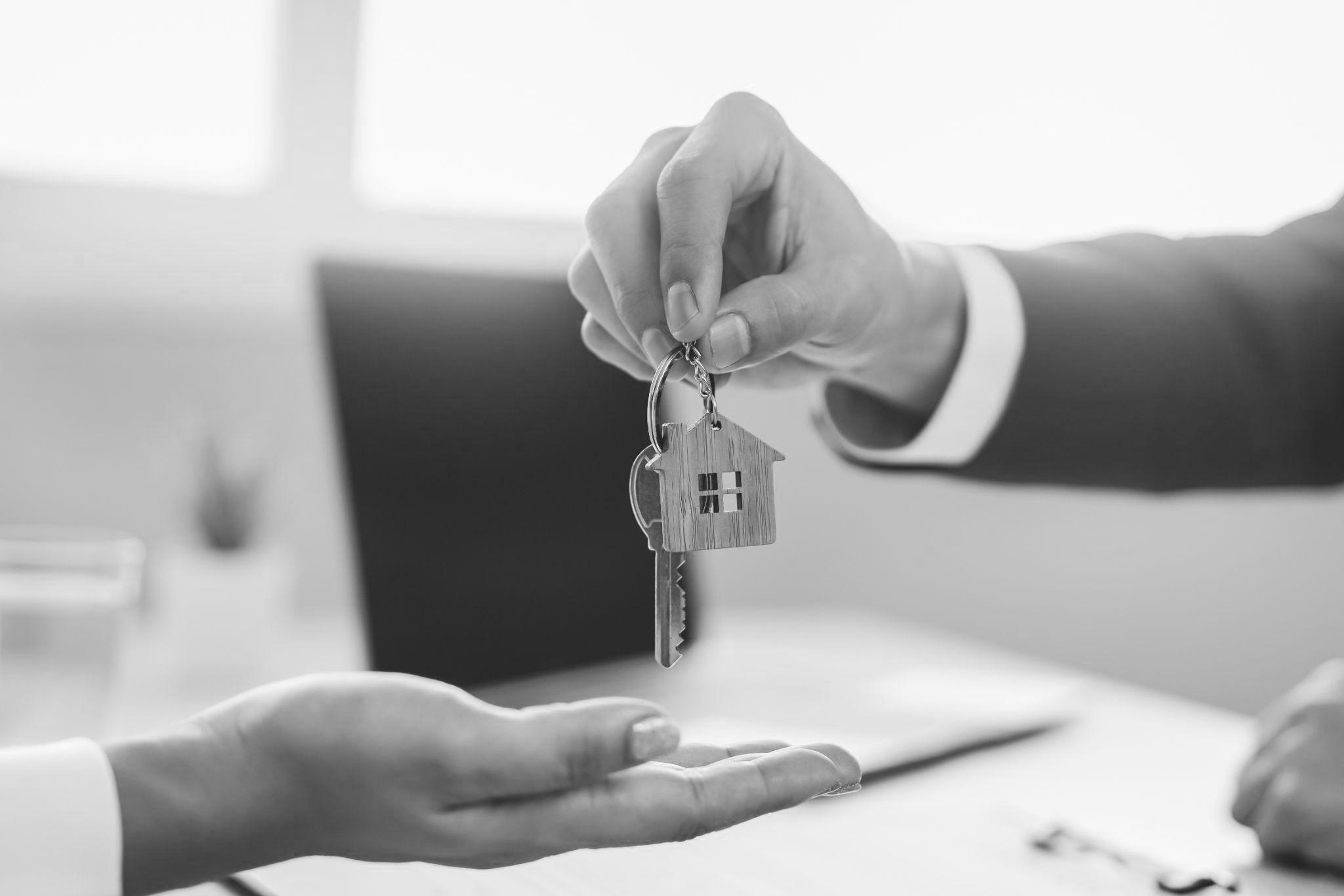close up view hand of property realtor giving key house to buyer