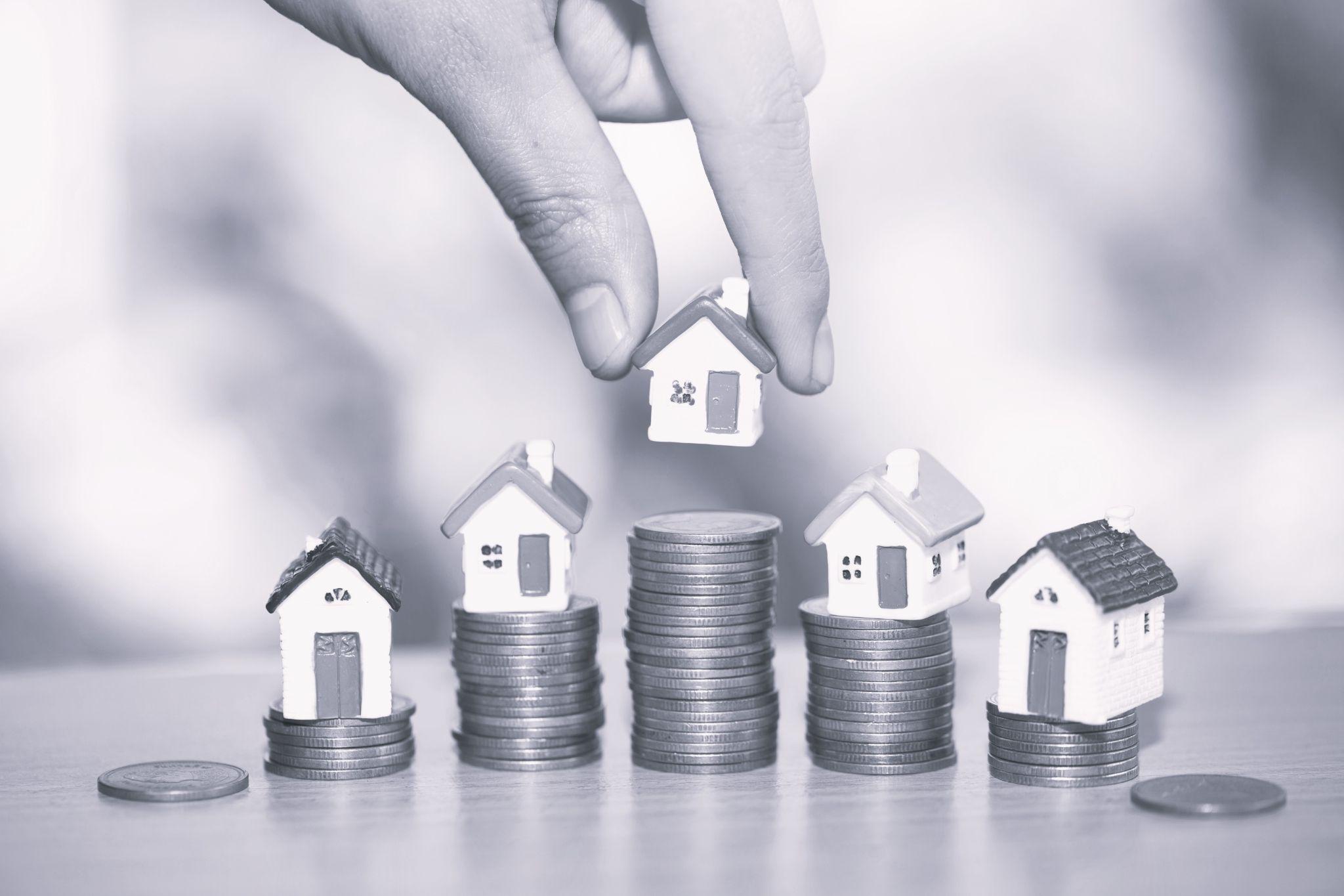 Woman hand hold a home model put on the stack coin with growing