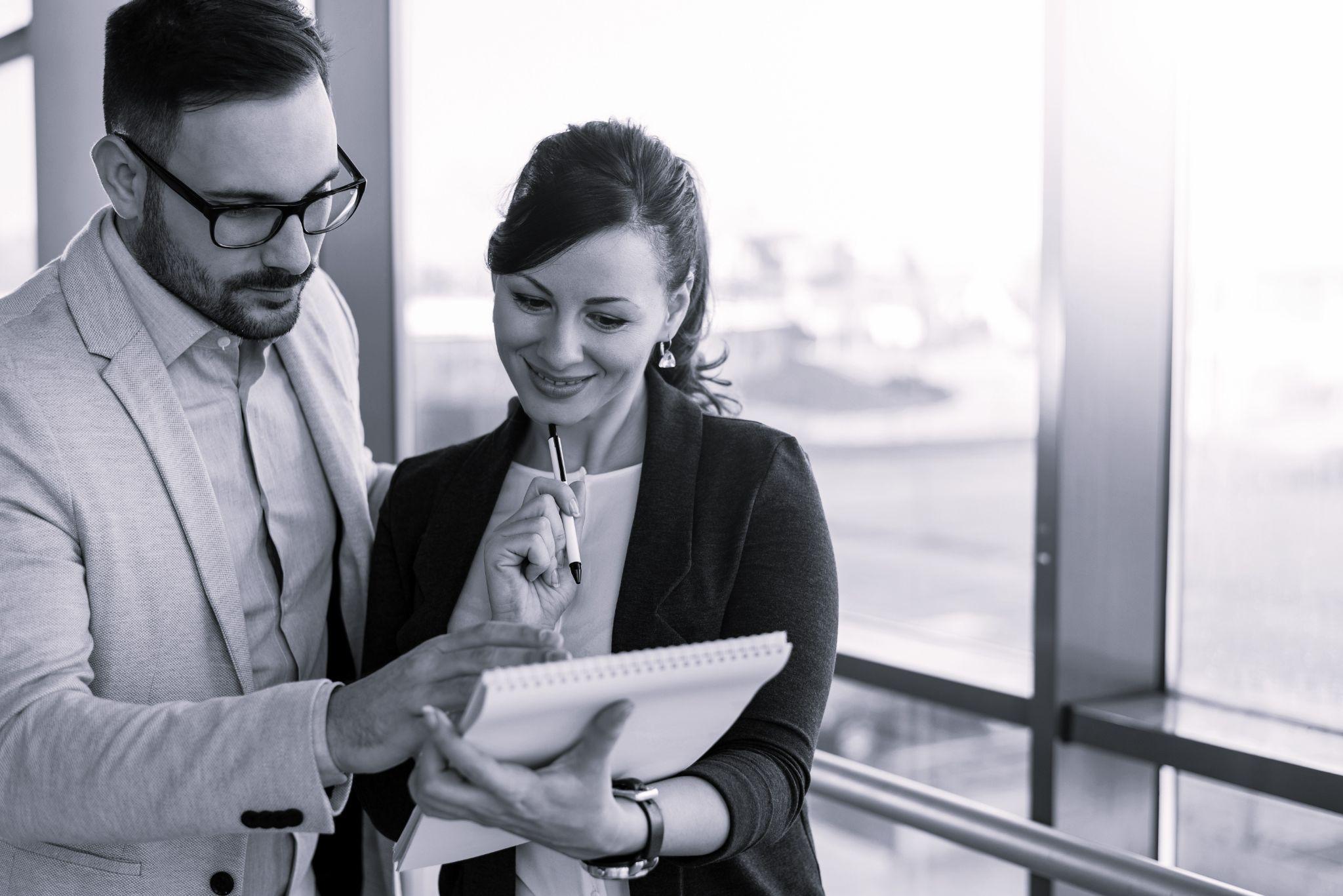 Two young business people talking about documents