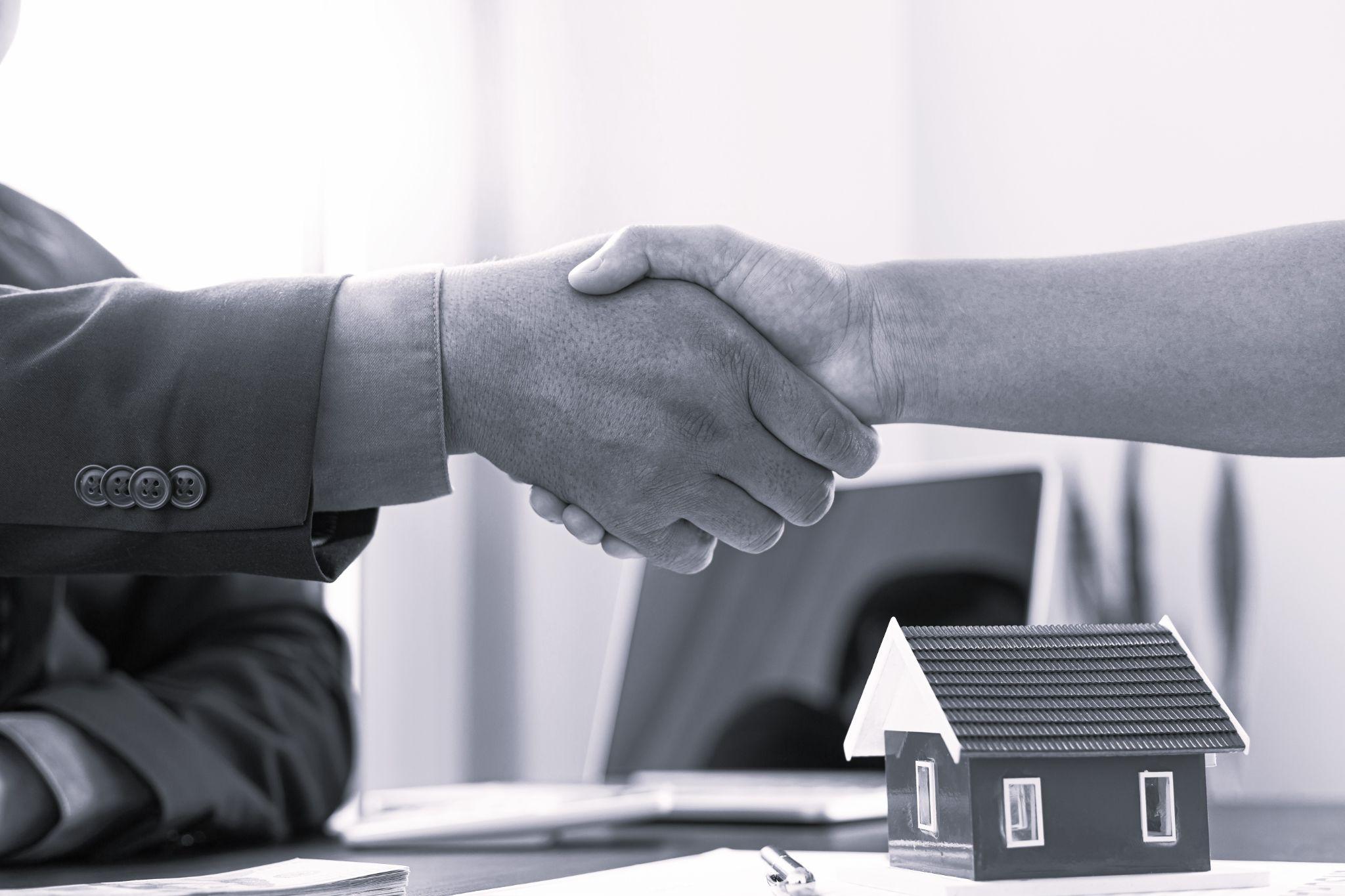 Home insurance agent shaking hand with the customer in the office.