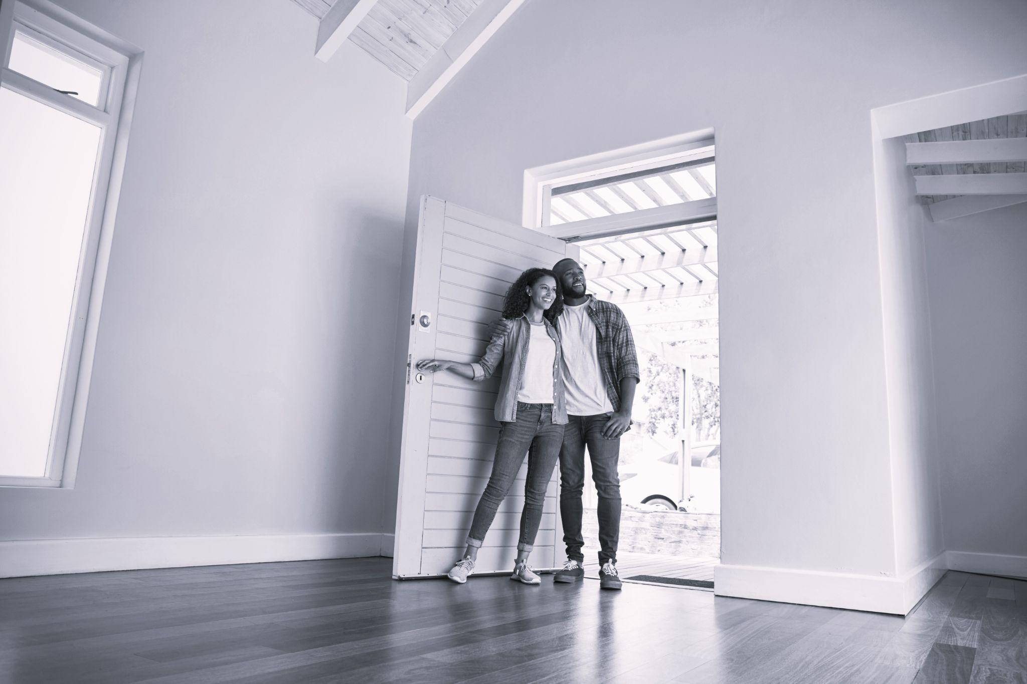 Couple opening door and walking in empty lounge of new home