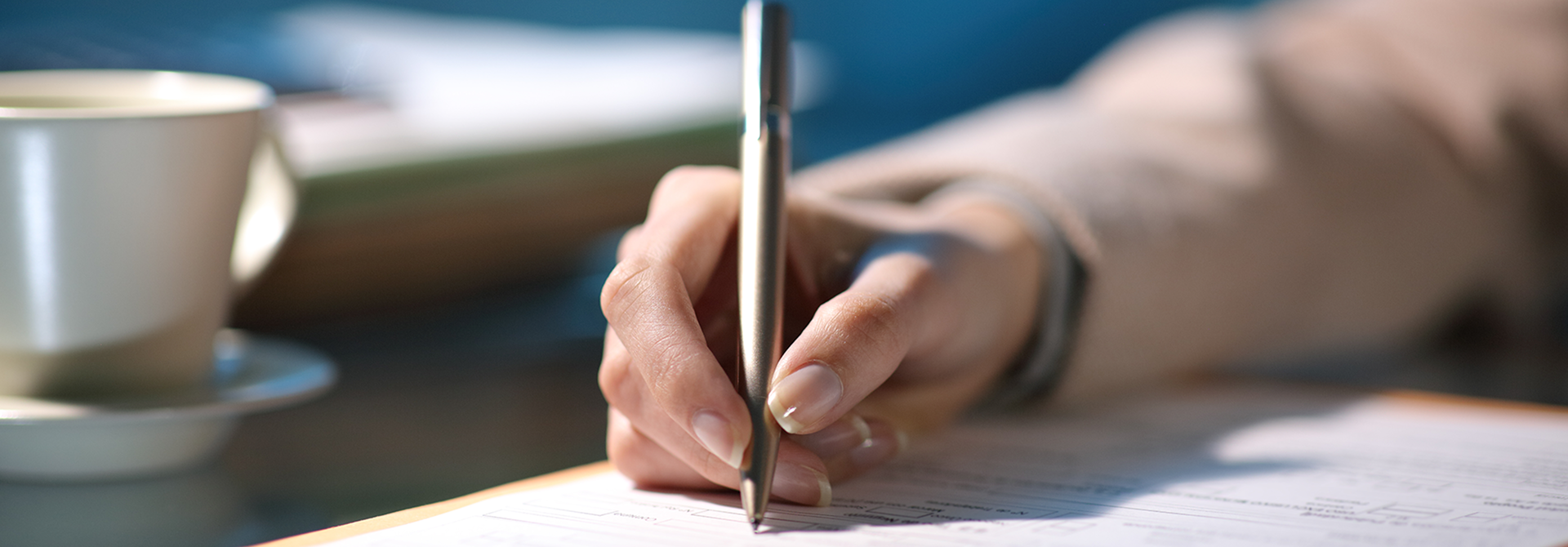 a person holding a pen and writing on a piece of paper a person holding a pen and writing on a piece of paper