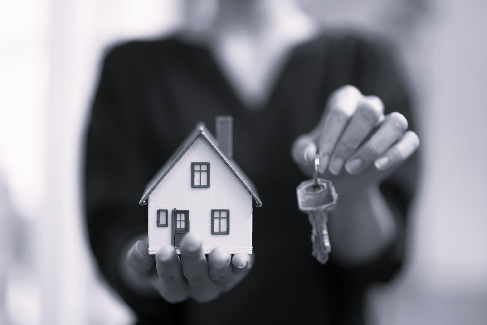 Woman holding a house miniature and keys