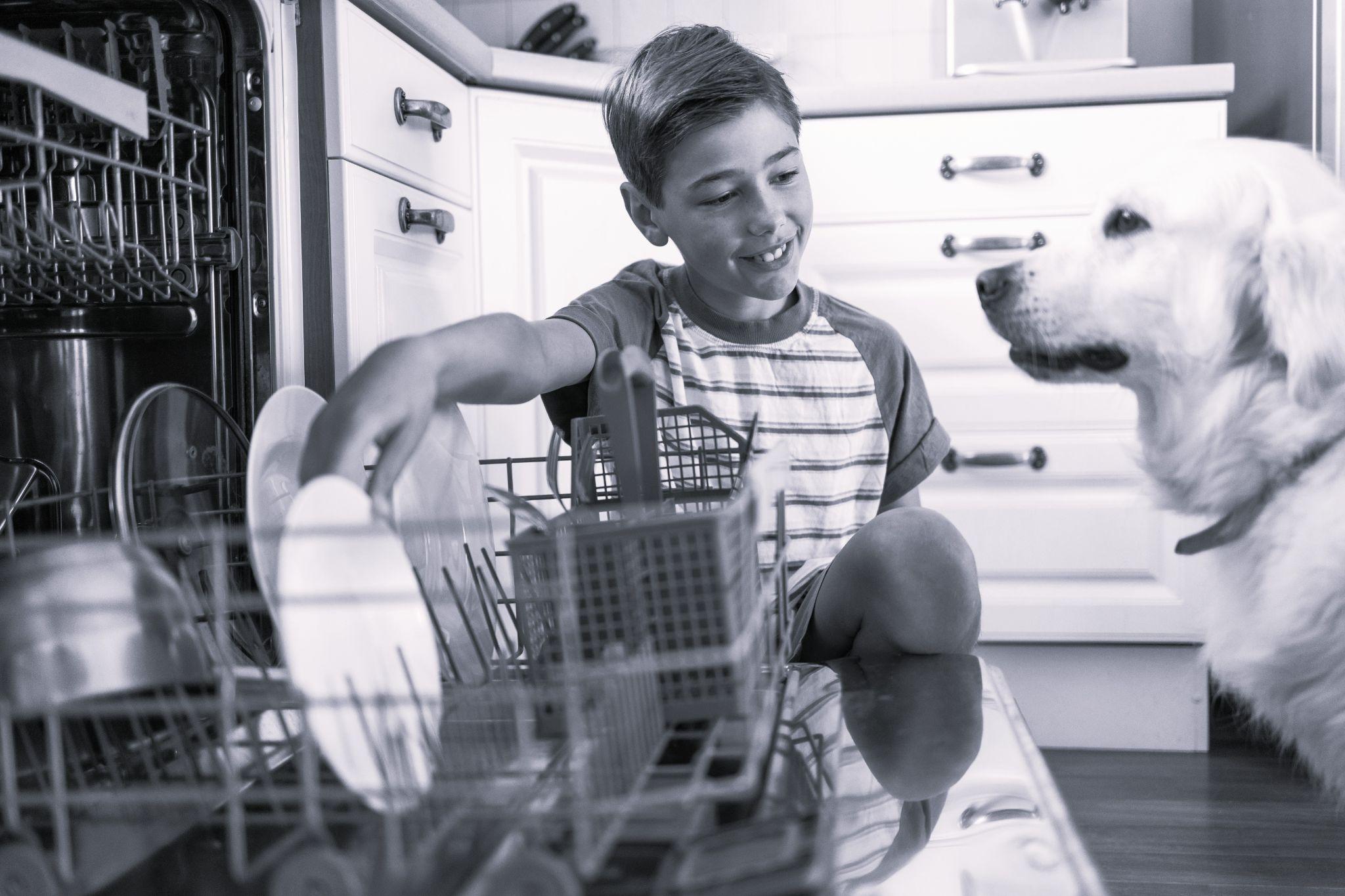 A young boy loading a dishwasher in a rental property.