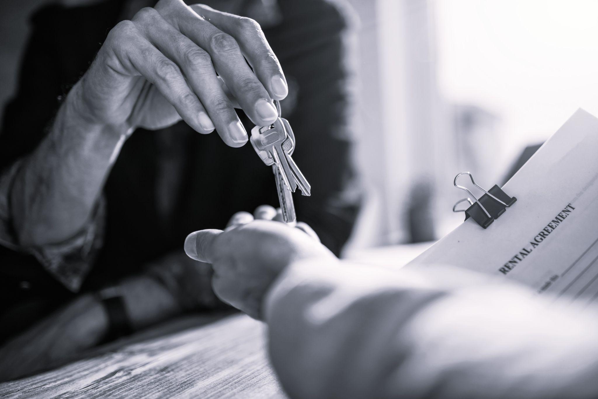 Closeup of a landlord handing over keys to a tenant